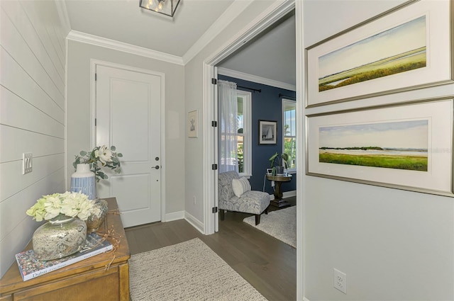 foyer entrance with dark wood-type flooring, ornamental molding, and baseboards