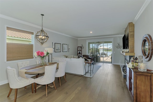 dining area featuring baseboards, ornamental molding, wood finished floors, and a chandelier