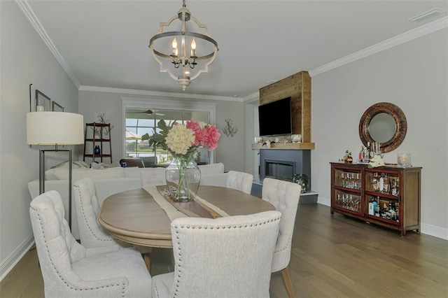 dining area featuring ornamental molding, a notable chandelier, a fireplace, and wood finished floors