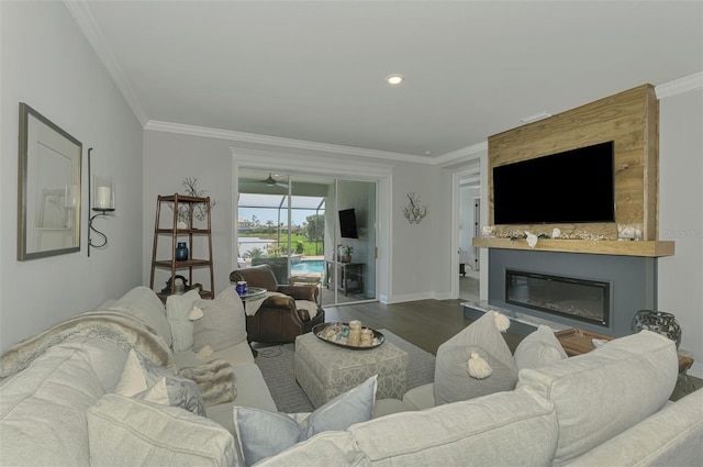 living area with a large fireplace, crown molding, baseboards, and wood finished floors