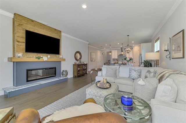 living room with recessed lighting, ornamental molding, a chandelier, a fireplace, and wood finished floors