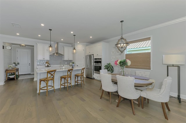 dining room with crown molding, recessed lighting, an inviting chandelier, visible vents, and wood finished floors