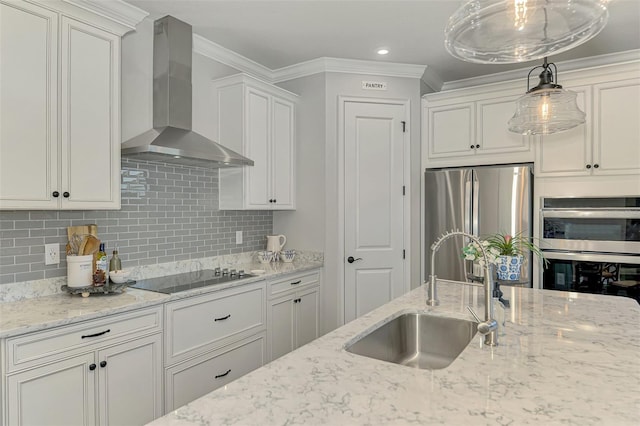 kitchen featuring crown molding, a sink, wall chimney exhaust hood, stainless steel appliances, and decorative backsplash
