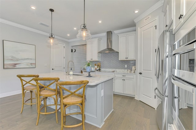 kitchen featuring visible vents, wall chimney range hood, crown molding, and appliances with stainless steel finishes