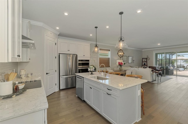 kitchen with open floor plan, white cabinetry, stainless steel appliances, under cabinet range hood, and a sink
