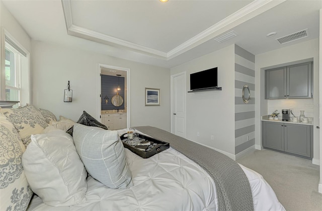 bedroom with a tray ceiling, light colored carpet, and visible vents