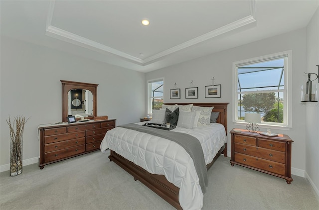 bedroom featuring ornamental molding, a tray ceiling, baseboards, and light colored carpet
