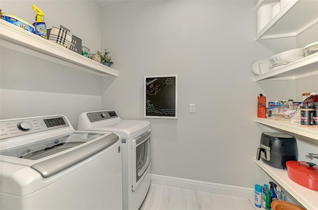 washroom with washing machine and clothes dryer, baseboards, and laundry area