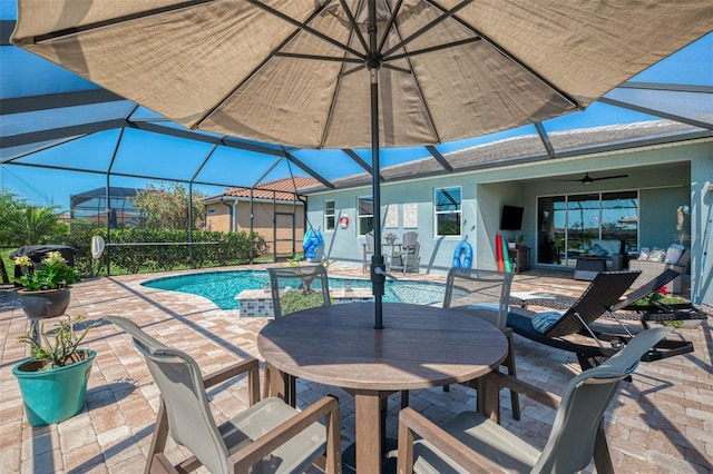 pool featuring glass enclosure, ceiling fan, outdoor dining area, and a patio area