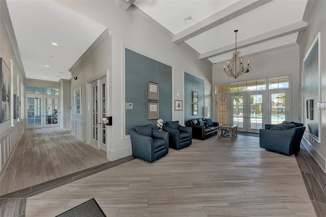 interior space featuring french doors, wood finish floors, an inviting chandelier, a towering ceiling, and beamed ceiling