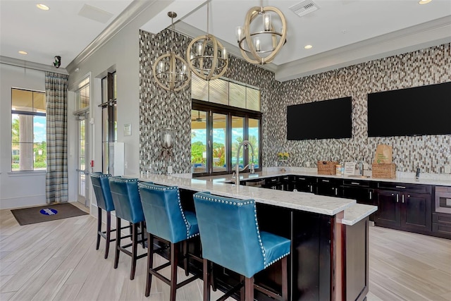 kitchen featuring ornamental molding, a sink, light stone counters, visible vents, and a notable chandelier