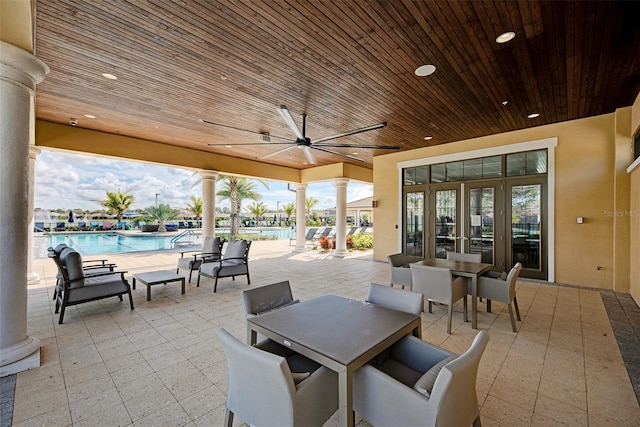 view of patio with a community pool, outdoor dining area, and a ceiling fan