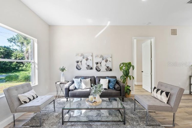 living area featuring baseboards, visible vents, and light wood-type flooring