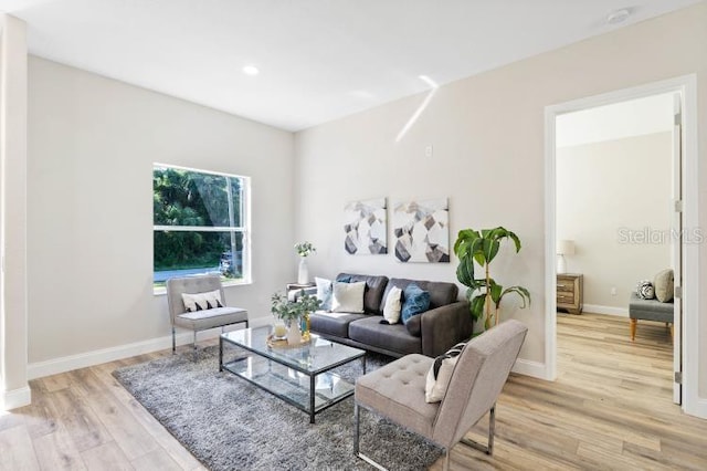 living room featuring baseboards, recessed lighting, and light wood-style floors