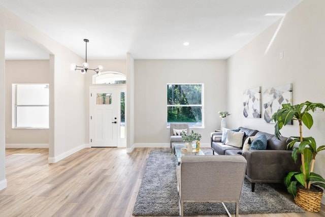 living room with baseboards, an inviting chandelier, and light wood finished floors