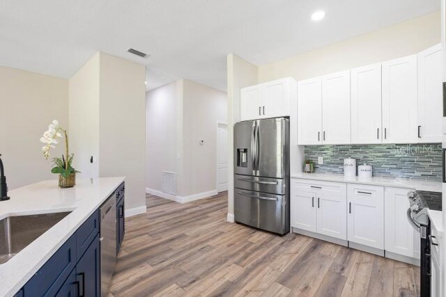 kitchen with visible vents, tasteful backsplash, appliances with stainless steel finishes, a sink, and light wood-style floors