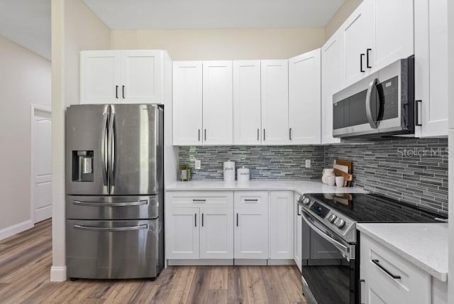kitchen with white cabinets, tasteful backsplash, appliances with stainless steel finishes, and wood finished floors