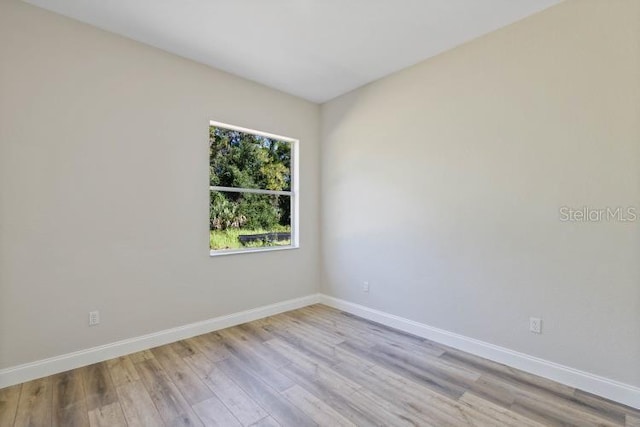 spare room featuring baseboards and light wood finished floors