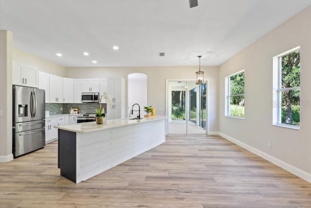kitchen featuring decorative backsplash, light countertops, white cabinets, appliances with stainless steel finishes, and a sink