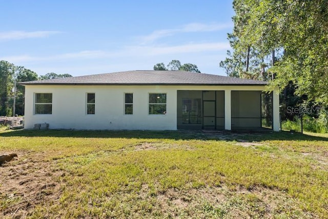 back of house with stucco siding, a sunroom, and a yard