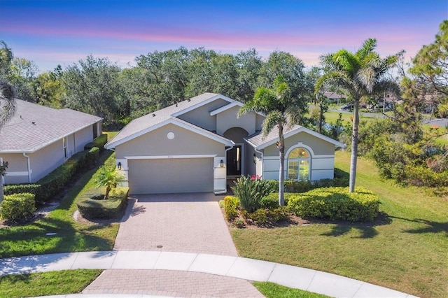 9312 Coachman Dr, Venice, FL 34293 - ranch-style house featuring stucco siding, decorative driveway, an attached garage, and a front lawn