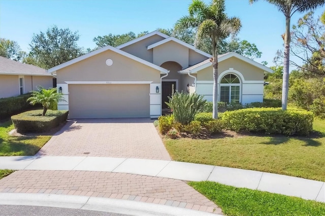 9312 Coachman Dr, Venice, FL 34293 - single story home with a front lawn, decorative driveway, an attached garage, and stucco siding