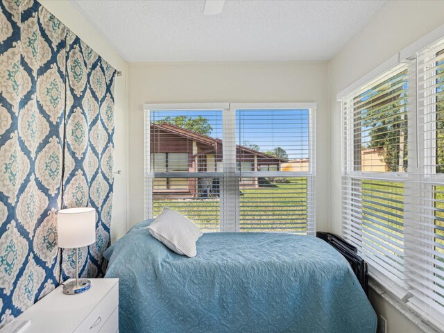 bedroom with a textured ceiling, multiple windows, and a ceiling fan