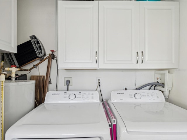laundry area featuring water heater, cabinet space, and washing machine and dryer