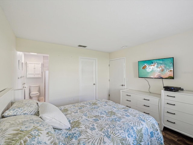 bedroom featuring dark wood-type flooring, ensuite bathroom, and visible vents