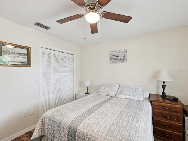 bedroom with baseboards, visible vents, a ceiling fan, a closet, and wood finished floors