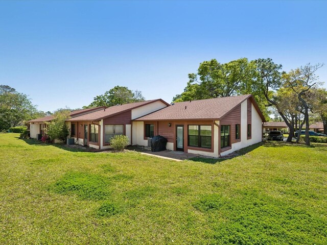 back of property featuring central air condition unit, a lawn, and roof with shingles