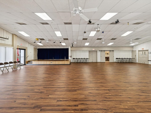 misc room with wood finished floors, a drop ceiling, and a ceiling fan
