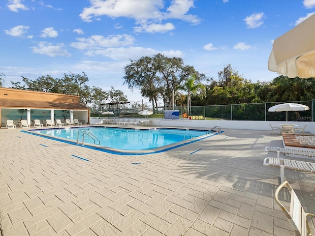 community pool with fence and a patio