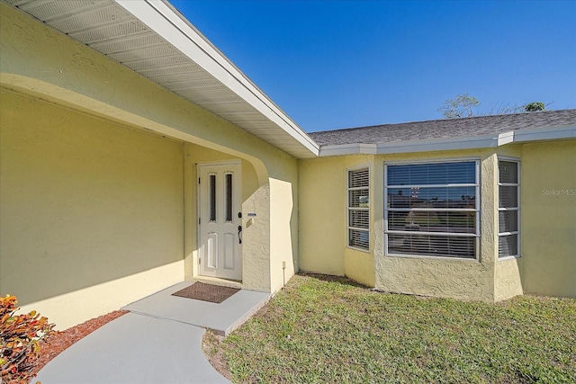 1003 N Gondola Dr, Venice, FL 34293 - view of exterior entry featuring stucco siding and a shingled roof