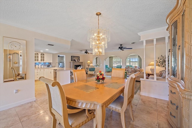 1003 N Gondola Dr, Venice, FL 34293 - dining space with light tile patterned floors, ceiling fan with notable chandelier, a fireplace, and crown molding
