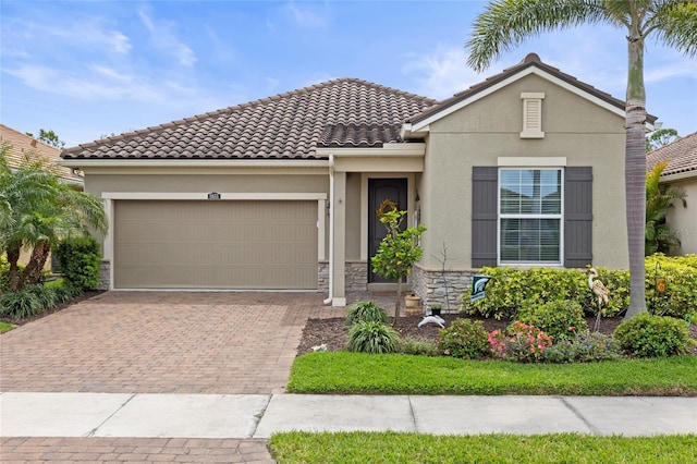 11655 Renaissance Blvd, Venice, FL 34293 - view of front of house featuring a tile roof, stone siding, stucco siding, decorative driveway, and a garage