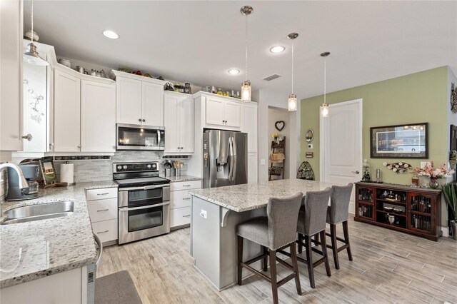 11655 Renaissance Blvd, Venice, FL 34293 - kitchen with a sink, backsplash, appliances with stainless steel finishes, light wood-style flooring, and visible vents