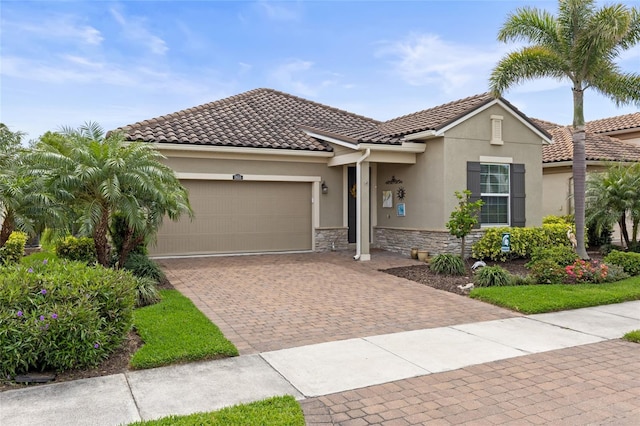 11655 Renaissance Blvd, Venice, FL 34293 - view of front of house featuring decorative driveway, a tiled roof, stucco siding, and an attached garage