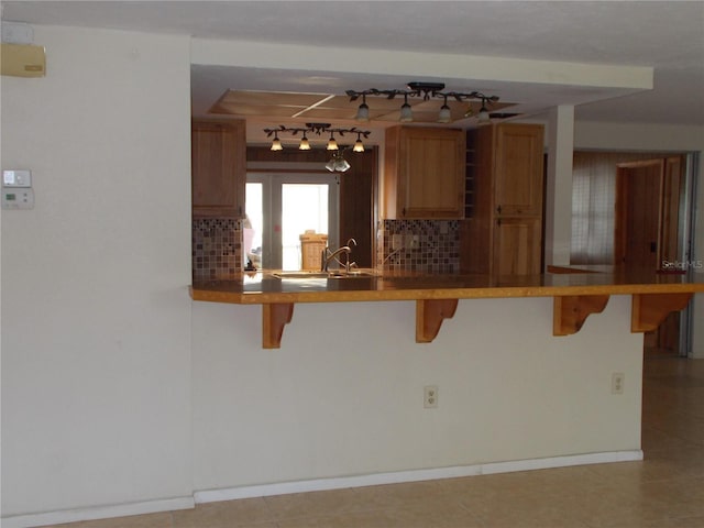 kitchen with a sink, backsplash, a kitchen bar, and a peninsula