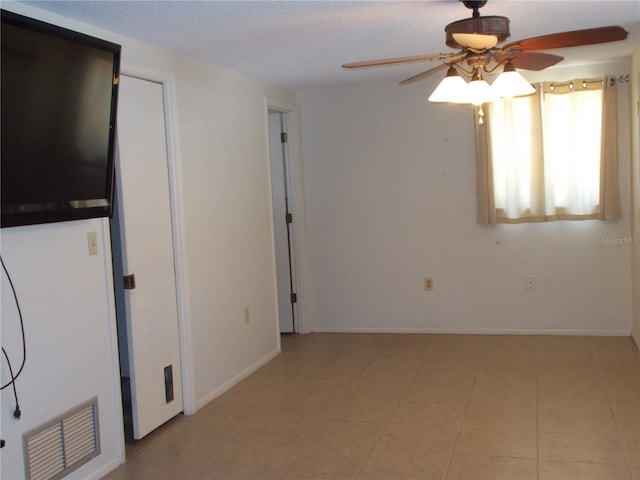 unfurnished room with a textured ceiling, visible vents, baseboards, ceiling fan, and light tile patterned floors