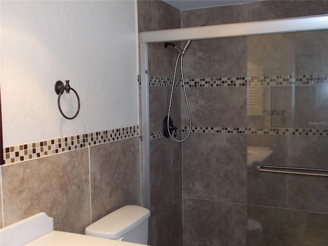 full bathroom with toilet, tile walls, and a shower stall