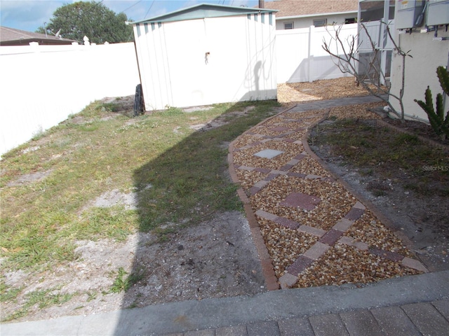 view of yard featuring a fenced backyard, an outbuilding, and a shed
