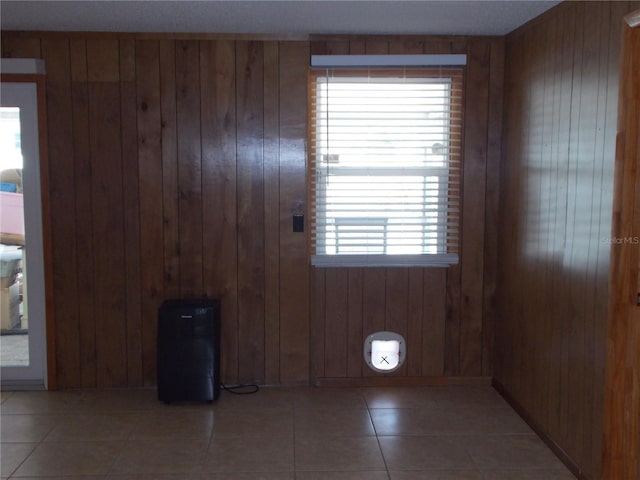 interior space with light tile patterned flooring and wooden walls