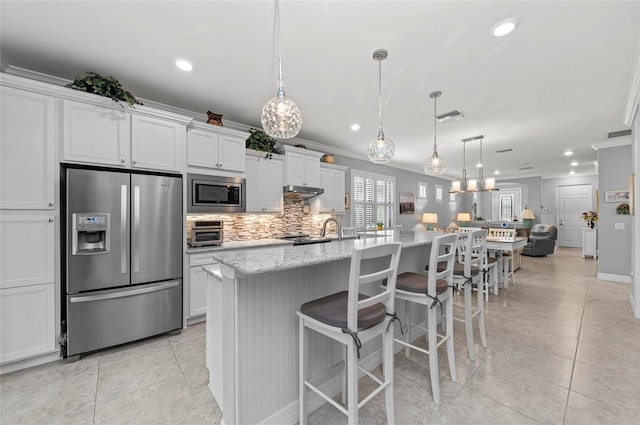 kitchen featuring decorative backsplash, visible vents, crown molding, stainless steel appliances, and an island with sink
