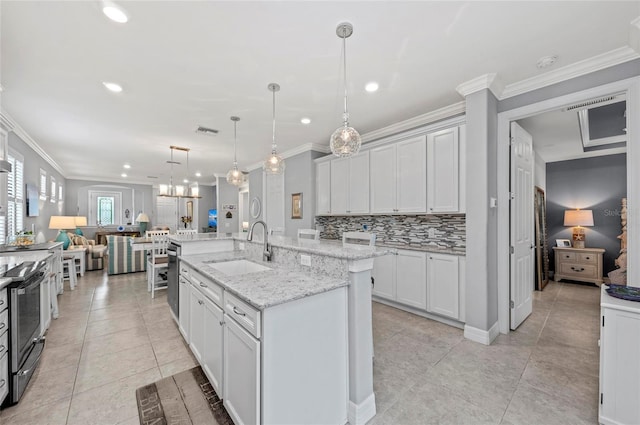 kitchen featuring open floor plan, ornamental molding, a sink, visible vents, and a kitchen island with sink