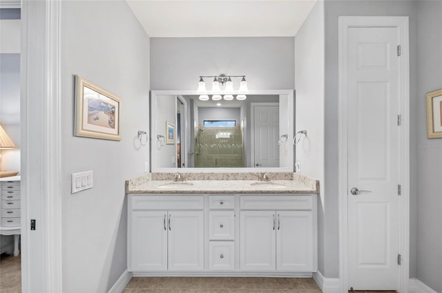 bathroom featuring double vanity, a sink, baseboards, and walk in shower