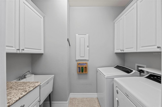washroom featuring electric panel, washing machine and clothes dryer, light tile patterned floors, baseboards, and cabinet space