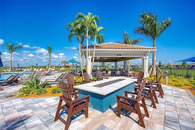 view of patio featuring a community pool, a gazebo, fence, and a ceiling fan