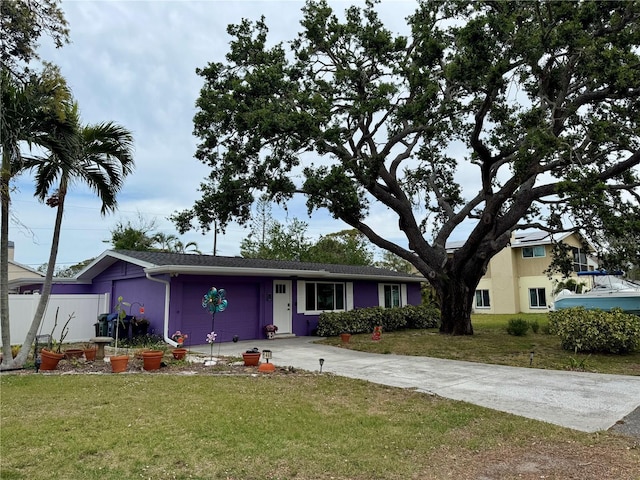 view of front facade featuring driveway, an attached garage, fence, and a front yard