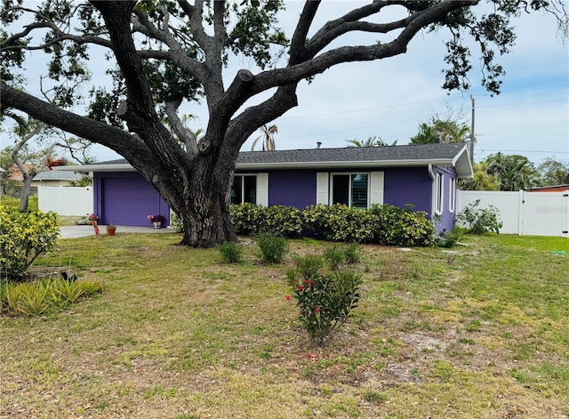ranch-style home featuring stucco siding, fence, an attached garage, a front yard, and a gate